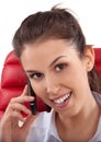 Beautiful business woman talking on mobile phone sitting on a red chair in office Royalty Free Stock Photo