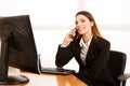 Beautiful business woman talks on smert phone in office at her d Royalty Free Stock Photo