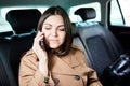 Beautiful business woman is using a smart phone and smiling while sitting on back seat in the car Royalty Free Stock Photo