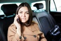 Beautiful business woman is using a smart phone and smiling while sitting on back seat in the car Royalty Free Stock Photo