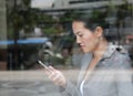 Beautiful business woman using a smartphone at reflection glass of office building