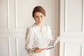 Beautiful business woman in a white shirt and dark pants holding a folder with documents. Royalty Free Stock Photo