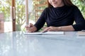 A beautiful business woman writing on blank notebook on table with green nature background Royalty Free Stock Photo