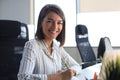 Beautiful business woman is writing something down while sitting in the office desk Royalty Free Stock Photo