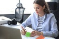 Beautiful business woman is writing something down while sitting in the office desk Royalty Free Stock Photo