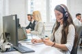 Beautiful business woman call operator with headset using mobile phone and writing notes to notebook at office desk. Royalty Free Stock Photo