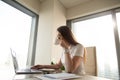 Beautiful businesswoman drinking coffee while working on laptop