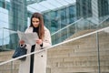 Beautiful businesswoman with handbag reading newspaper outdoor