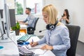 Beautiful businesswoman with headset analyzing business document at office desk. Royalty Free Stock Photo