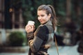 Beautiful businesswoman holding coffee cup and walking on city street to the work at spring time. Royalty Free Stock Photo