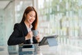 Beautiful businesswoman holding a cup of coffee relaxing happily working through a tablet for a successful business while sitting Royalty Free Stock Photo