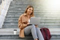 Beautiful businesswoman with laptop sitting on stairs outdoors Royalty Free Stock Photo