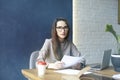 Beautiful businesswoman with long hair working with documentation, sheet, laptop while sitting in modern loft office. Royalty Free Stock Photo