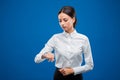 Beautiful businesswoman seriously looking at her watch, on blue background