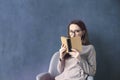 Beautiful businesswoman sitting in loft office reading vintage book. Look into opened book brown cover. Dark blue wall background