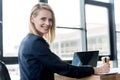 beautiful businesswoman smiling at camera while using laptop and taking notes Royalty Free Stock Photo