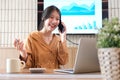 Beautiful businesswoman using a smartphone and working with a laptop while sitting at an office desk, working from home concept Royalty Free Stock Photo