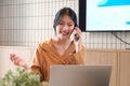 Beautiful businesswoman using a smartphone and working with a laptop while sitting at an office desk, working from home concept Royalty Free Stock Photo