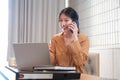 Beautiful businesswoman using a smartphone and working with a laptop while sitting at an office desk, working from home concept Royalty Free Stock Photo