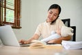 Beautiful busy Asian mother working from home, talking on the phone and holding her baby Royalty Free Stock Photo