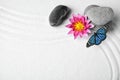 Beautiful butterfly, flowers and stones on white sand with pattern, flat lay. Zen concept Royalty Free Stock Photo