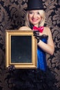 Beautiful cabaret woman posing with golden frame against retro w