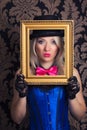 Beautiful cabaret woman posing with golden frame against retro w Royalty Free Stock Photo