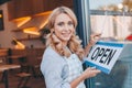 beautiful cafe owner in apron holding sign open and smiling Royalty Free Stock Photo