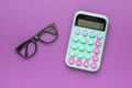 Beautiful calculator and glasses on a purple background Royalty Free Stock Photo