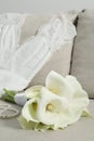 Beautiful calla lily flowers tied with ribbon, wedding dress and necklace on sofa