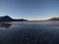 Beautiful calm blue waves hitting white frozen sandy beach in late autumn in the arctic circle with deep mountain and open sea