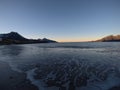 Beautiful calm blue waves hitting white frozen sandy beach in late autumn in the arctic circle with deep mountain and open sea vie