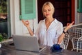 Beautiful and calm business woman sitting at a table with a laptop in a summer cafe in the lotus position meditating and Royalty Free Stock Photo