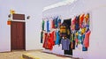 Beautiful calm empty alley, clothing boutique, hanging traditional colorful clothes, flawless bright white typical walls, blue