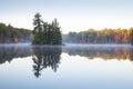 Beautiful calm lake with trees in autumn color and a small island in northern Minnesota at dawn Royalty Free Stock Photo