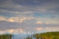 A beautiful calm and quiet view of lake water with a cloudy sky reflection and green grass on the bank. The landscape of Royalty Free Stock Photo