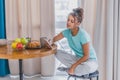 Beautiful young woman sitting on a chair next to the window. Having a fresh croissant and a glass of orange juice for Royalty Free Stock Photo