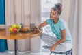 Beautiful young woman sitting on a chair next to the window. Having a fresh croissant and a glass of orange juice for Royalty Free Stock Photo