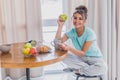 Beautiful young woman sitting on a chair next to the window. Having a fresh croissant and a glass of orange juice for Royalty Free Stock Photo