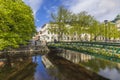 Beautiful calming cityscape view with bridge over small river decorated with flowers.