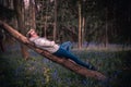 Beautiful calming sight of a young attratcive man laying on a bent tree in a forest with wildflower