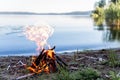 Beautiful campfire in the evening at lake. Fire burning in dusk at campsite