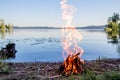 Beautiful campfire in the evening at lake. Fire burning in dusk at campsite