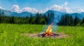 beautiful campfire in the middle of a meadow by day with big mountains