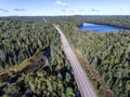 Beautiful Canada camper bus driving on road endless pine tree forest with lakes moor land aerial view travel background Royalty Free Stock Photo