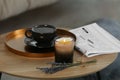 Beautiful candle, lavender, newspaper and cup of coffee on round wooden table indoors Royalty Free Stock Photo