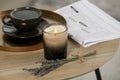 Beautiful candle, lavender, newspaper and cup of coffee on round wooden table indoors Royalty Free Stock Photo