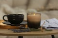 Beautiful candle, lavender, newspaper and cup on round wooden table in living room, closeup