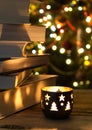 Beautiful candle on a wooden table with a stack of books and christmas garlands on the background Royalty Free Stock Photo