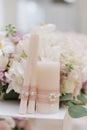 Beautiful candles decorated with thin pink lace and a small brooch against the background of wedding flowers Royalty Free Stock Photo